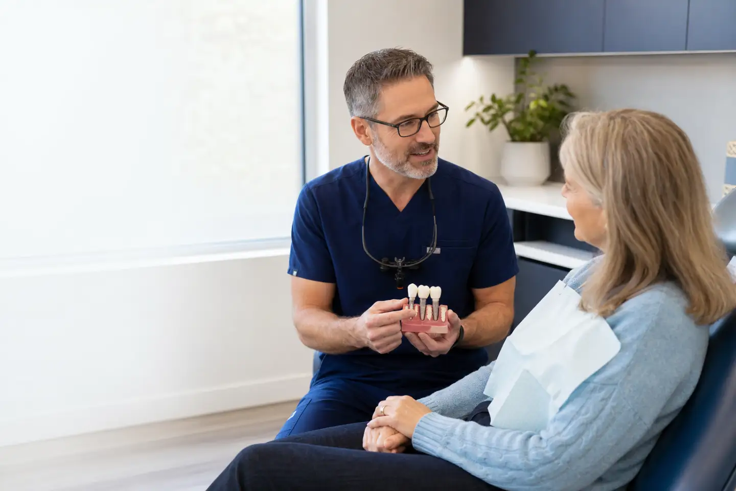 Dentist showing a dental bridge model to a patient